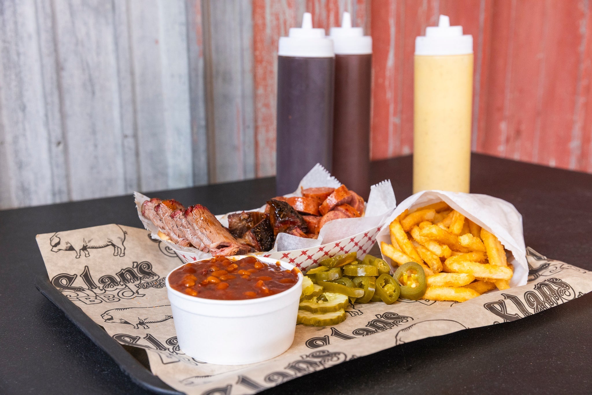 Tray of Slap's BBQ smoked meats, sides, and sauce